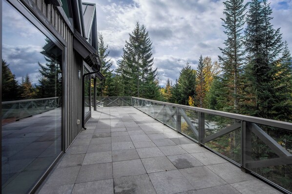 A modern building with a glass balcony overlooking a forested area. - Pinnacle Ridge 3 - Ski in Ski out, 7 Bedrooms, Hot Tub, Sauna & Billiards (Whistler)