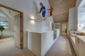 A modern interior with a sloped ceiling, a staircase, and a wall-mounted sculpture. - Pinnacle Ridge 3 - Ski in Ski out, 7 Bedrooms, Hot Tub, Sauna & Billiards (Whistler)
