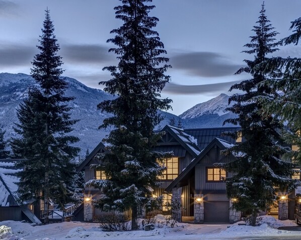 A snow-covered lodge with a mountain backdrop, featuring a prominent entrance and multiple windows. - Pinnacle Ridge 3 - Ski in Ski out, 7 Bedrooms, Hot Tub, Sauna & Billiards (Whistler)