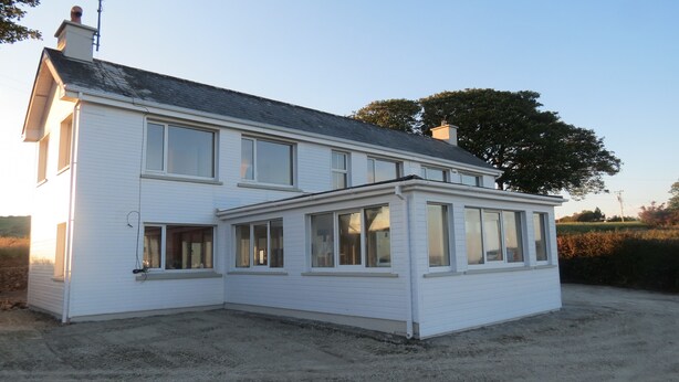 Een huis met twee verdiepingen, een ruime veranda en veel ramen.