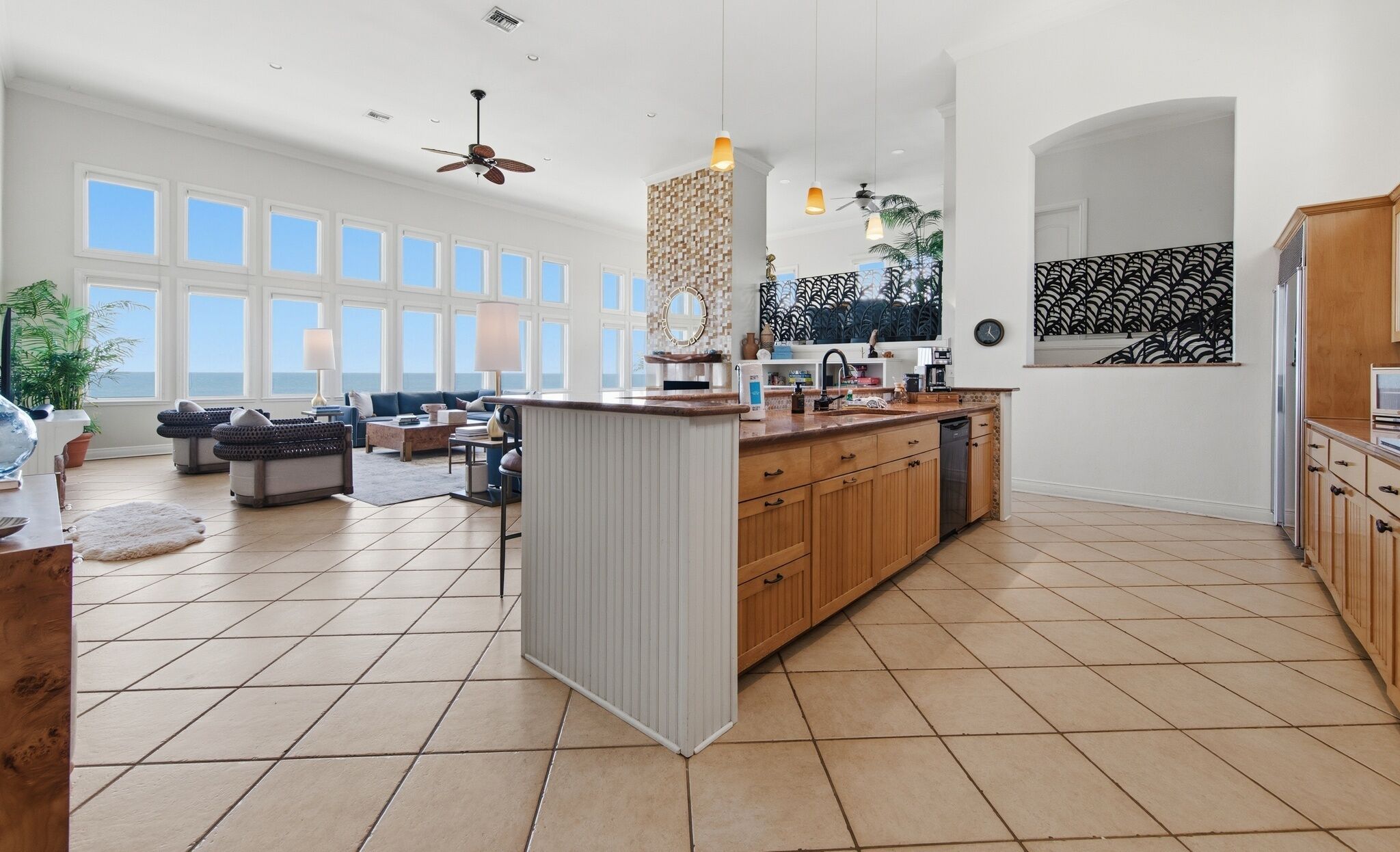Una cocina amplia con una isla central, ventanas grandes y vista al océano.