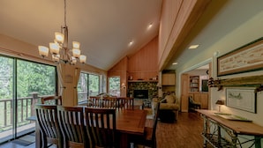 Un comedor amplio con una mesa y sillas de madera, un candelabro y vistas al exterior.