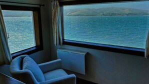 A cabin with a view of the sea, a window, and a chair. - Bleu Bay | Charming Coastal Cottage, Private Beach (Marshall)