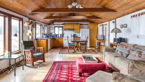 A spacious living area with a wooden ceiling, a dining table, and a sofa. - Bleu Bay | Charming Coastal Cottage, Private Beach (Marshall)