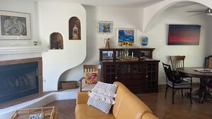 A living room with a fireplace, a sofa, a dining table with chairs, and various decorative items on the walls. - Palm Springs Paradise (Palm Springs)