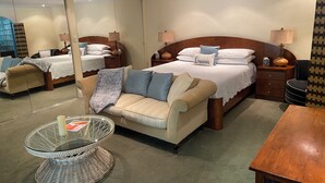 A bedroom with a large bed, a sofa, a glass-top table, and a wooden side table. - Palm Springs Paradise (Palm Springs)