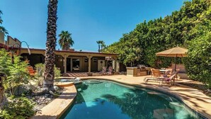 A swimming pool with a patio area, lounge chairs, and a covered seating area. - Palm Springs Paradise (Palm Springs)