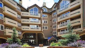 Un hôtel à plusieurs étages doté d’une cour intérieure, de balcons à chaque étage et d’une grande variété de plantes et de fleurs disposées tout autour.