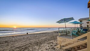 A beach with a glass-walled lounge area, outdoor seating, and a staircase leading to a building. - 3 Bedroom Oceanfront Paradise! (Carlsbad)