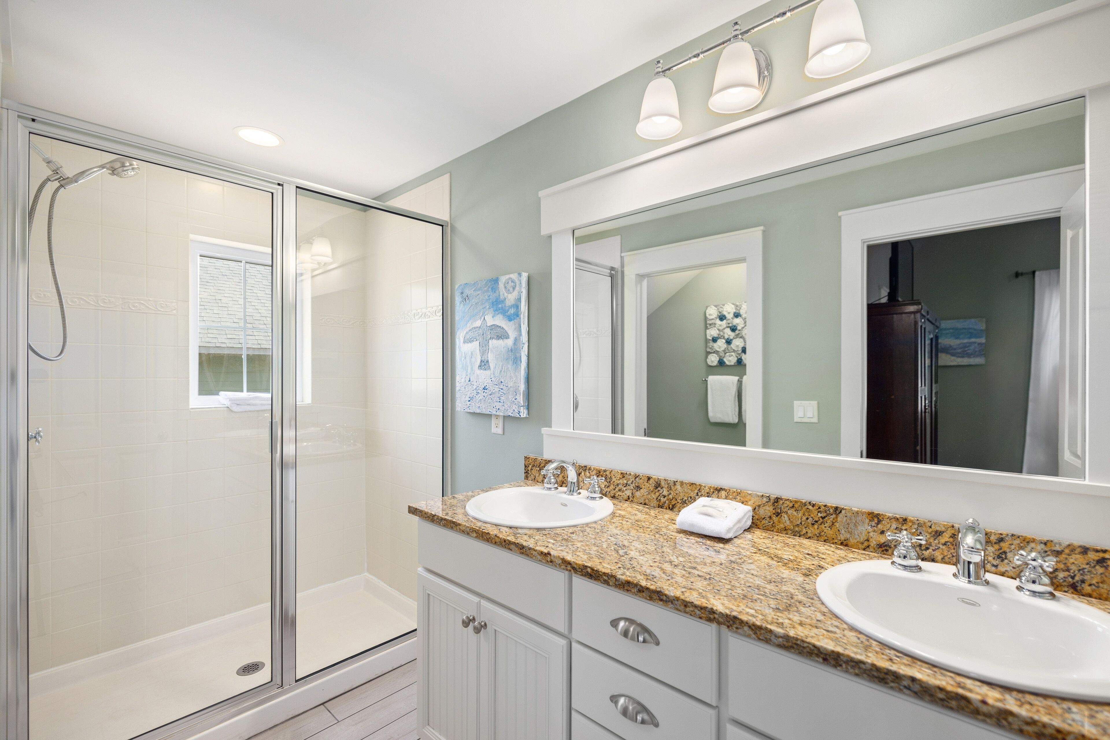 A bathroom with two sinks, a large mirror, and a shower area.