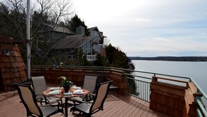 Une terrasse avec une table dressée pour le dîner, donnant sur un lac.