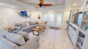Ein modernes Wohnzimmer mit einem grauen Sofa, einem Holztisch und einem Deckenventilator.