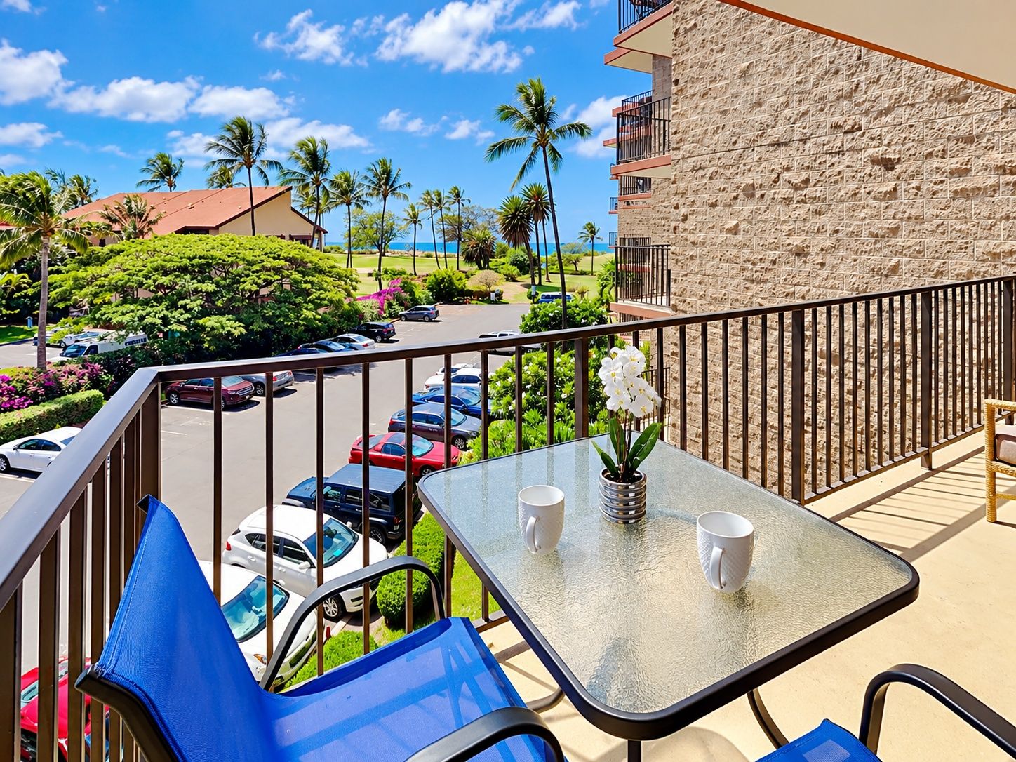 A balcony with a table, chairs, and a potted plant.