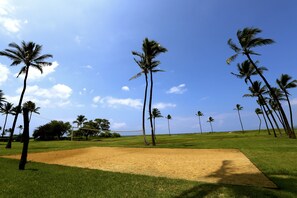 A sandy volleyball court surrounded by palm trees under a clear sky. - Scenic Kihei Village by the Sea Renovated Condo Ocean Views Lanai Pool (Kihei)