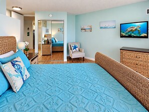 A bedroom with a large bed, a chair, a dresser, and a television on the wall. - Scenic Kihei Village by the Sea Renovated Condo Ocean Views Lanai Pool (Kihei)