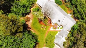 An aerial view of a house with a large lawn, a tree, and a small garden area.