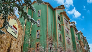Ein mehrstöckiges Gebäude mit grüner Fassade und zahlreichen Fenstern.