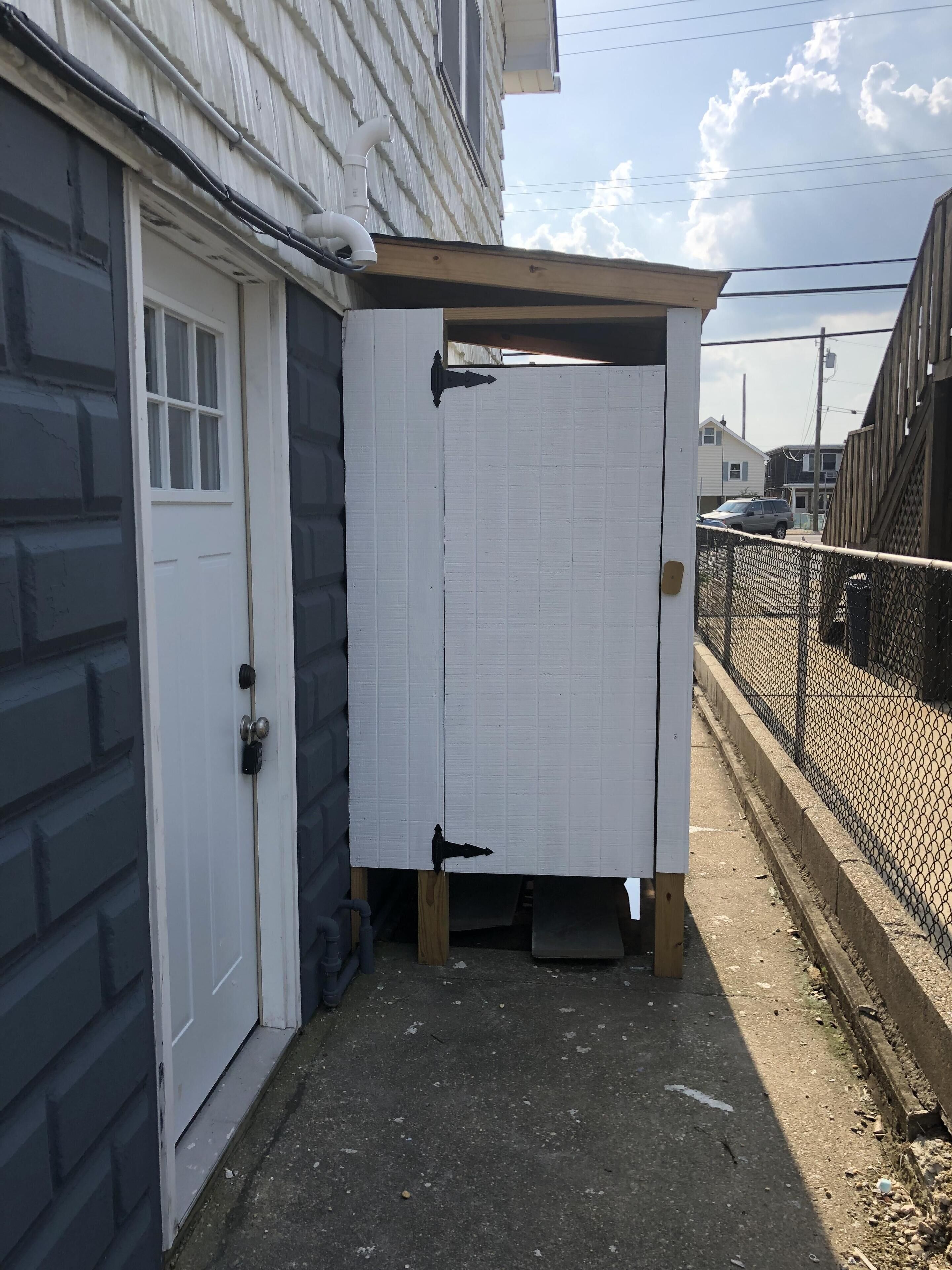 Un espacio exterior pequeño y cerrado, con una puerta blanca y una estructura de madera.