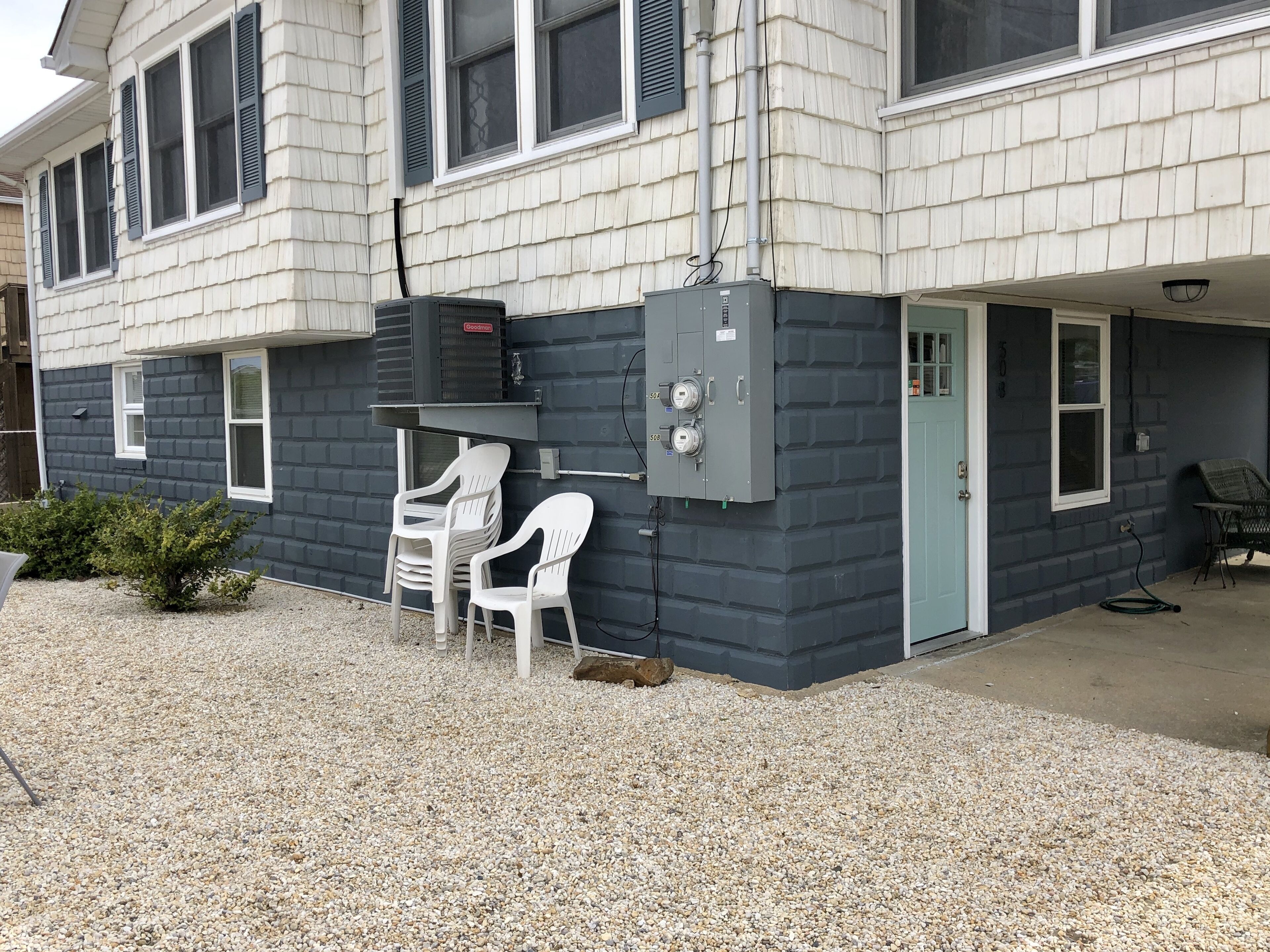 Un bâtiment à deux étages doté d’un espace extérieur couvert avec des sièges, d’un barbecue et d’un local technique.