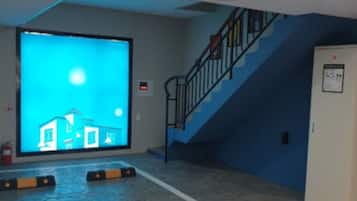 Una habitación con una pantalla grande que muestra un edificio, una escalera y un extintor.