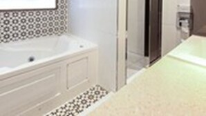 Un baño moderno con una bañera grande, cabina de ducha con vidrio y un salpicadero de azulejos estampados.
