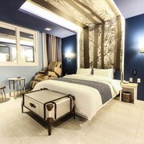 Habitación de hotel moderna con cama, mesitas de noche, una silla y vistas al exterior.