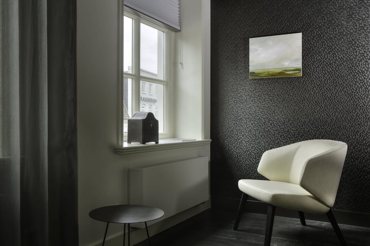 A room with a window, a radiator, a chair, and a small table.