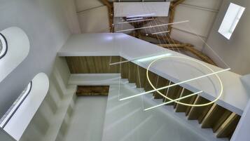 A modern staircase with wooden steps and white walls, leading to a lofted area with a sloped ceiling.
