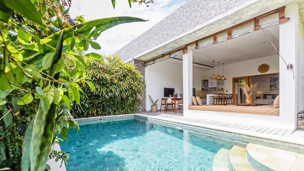 A modern house with a swimming pool, a patio with outdoor furniture, and a view of the interior.