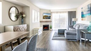 A modern living room with a fireplace, a dining area, and a sofa set.