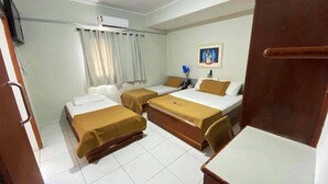 Habitación de hotel con dos camas, un escritorio, una silla, un televisor y un aire acondicionado.