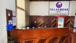 Una mesa de recepción con un cartel que indica Villas Boas Hotel y un refrigerador de Coca-Cola.