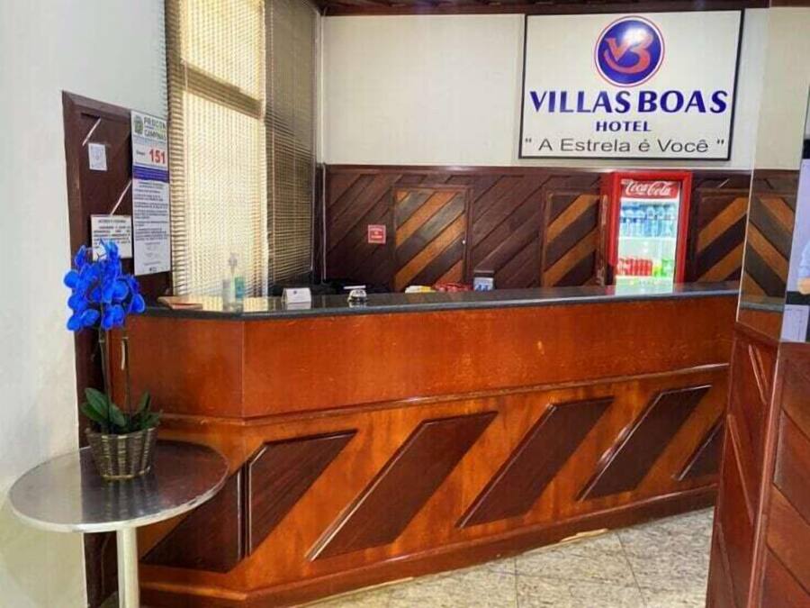 Uma receção com uma placa a indicar o Hotel Villas Boas e um refrigerador de Coca-Cola.