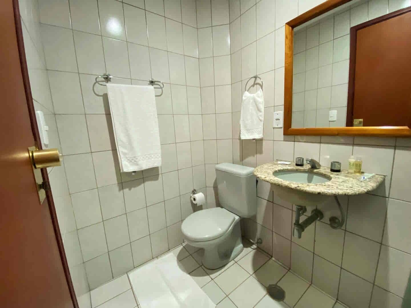 Et lille badeværelse med toilet, vask og spejl.