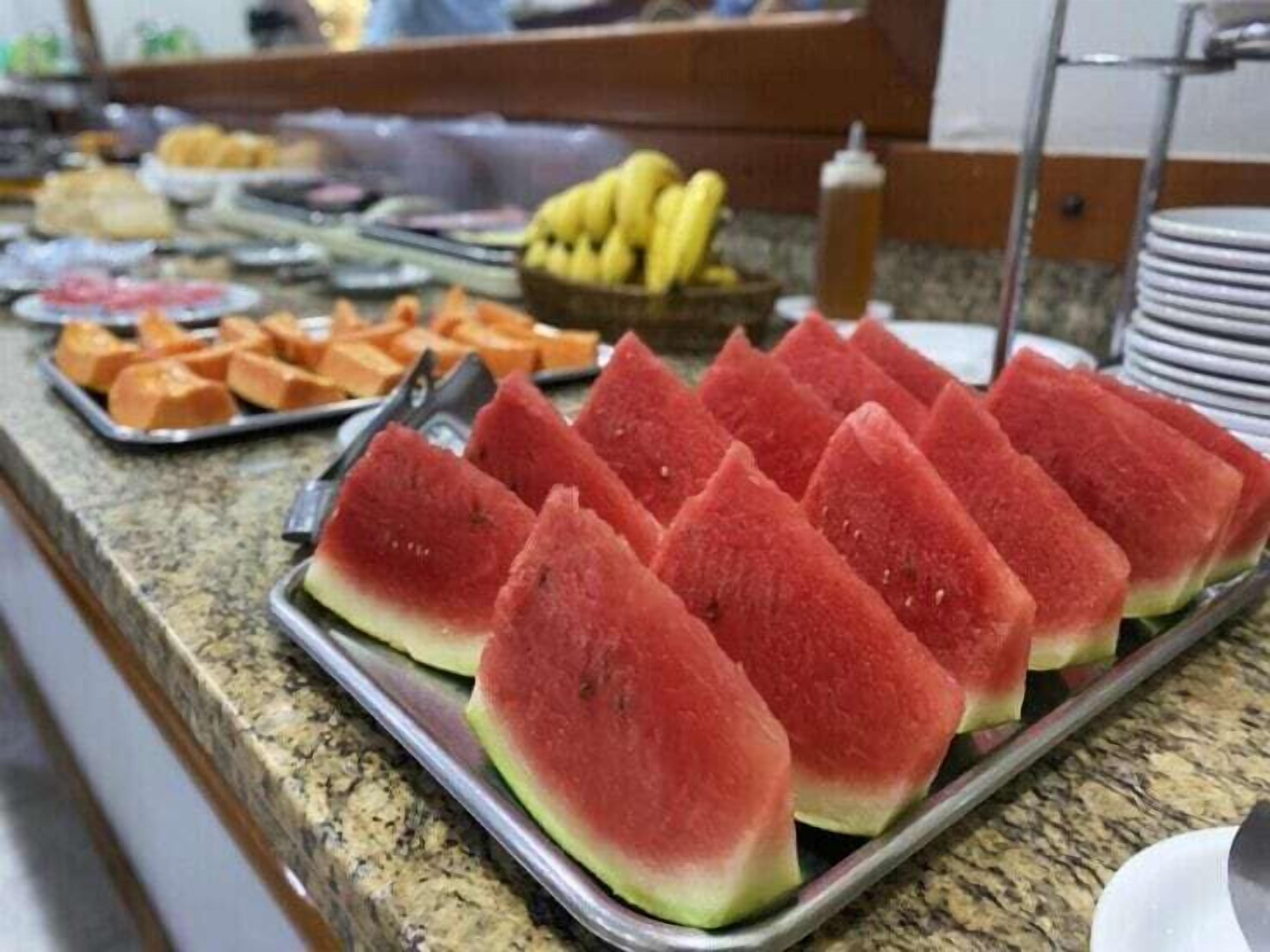 A buffet with various food items including watermelon slices, fruits, and other dishes.