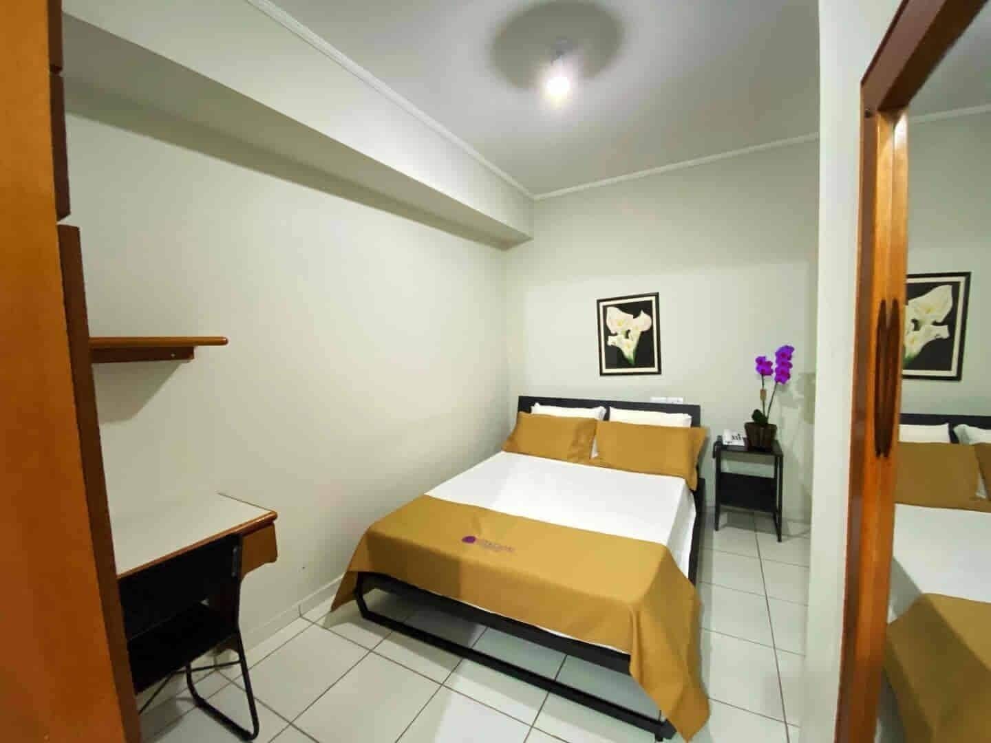 Un dormitorio con cama, mesita de noche y escritorio.