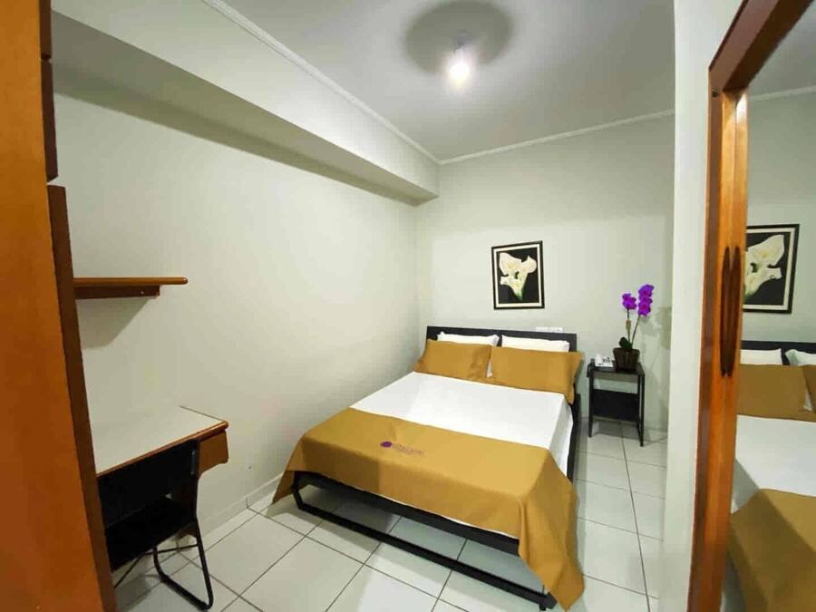Un dormitorio con cama, mesita de noche y escritorio.