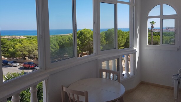 Una habitación con amplios ventanales que dan a vistas del mar y vegetación.