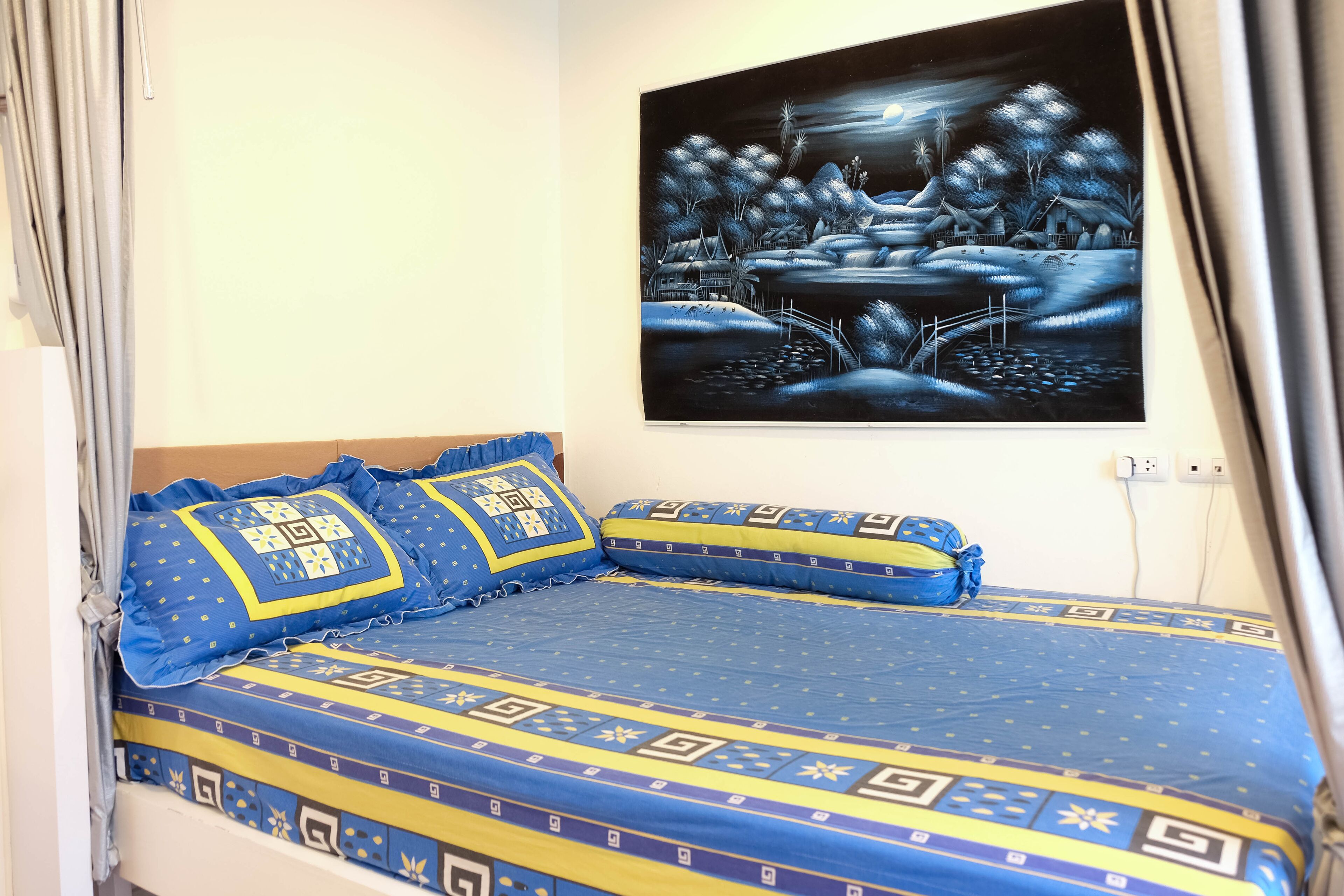Ein Schlafzimmer mit einem Bett, Kissen und einem Wandbild.