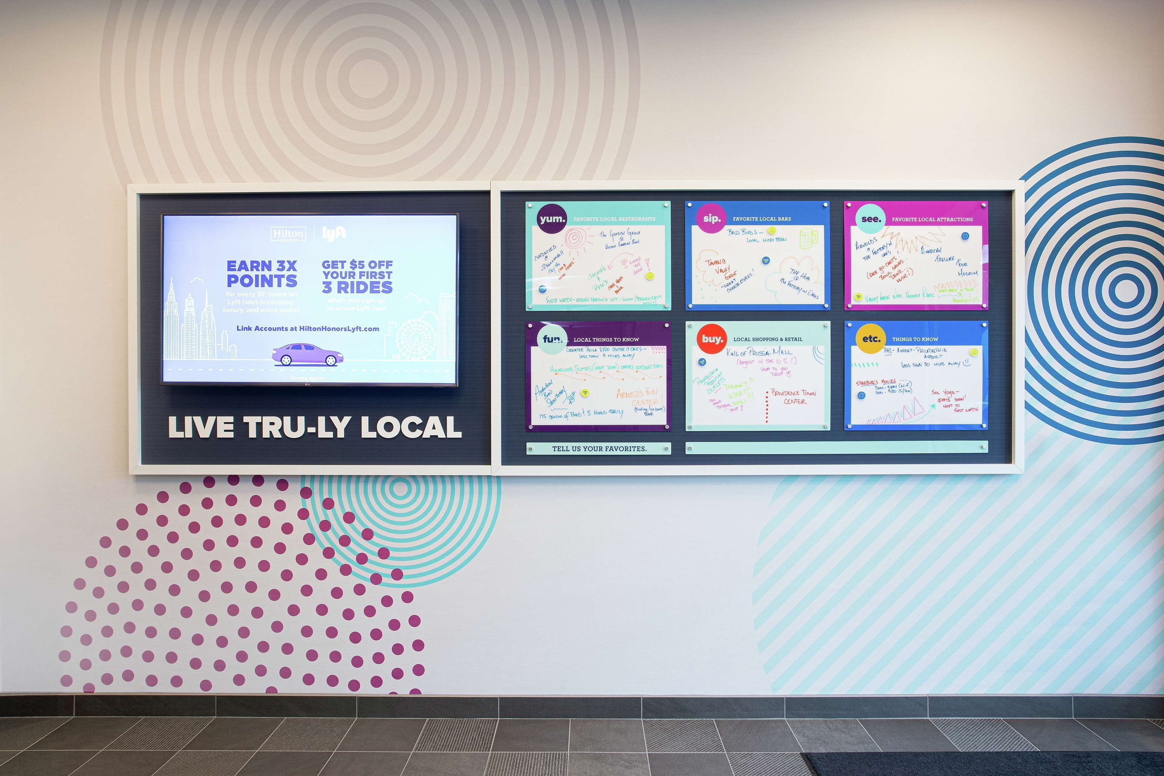 A wall with various promotional posters and a digital display.