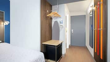 Habitación de hotel compacta con cama, una mesita, un armario y un espejo.