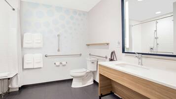 A modern bathroom with a white toilet, a sink with a wooden vanity, and a mirror.