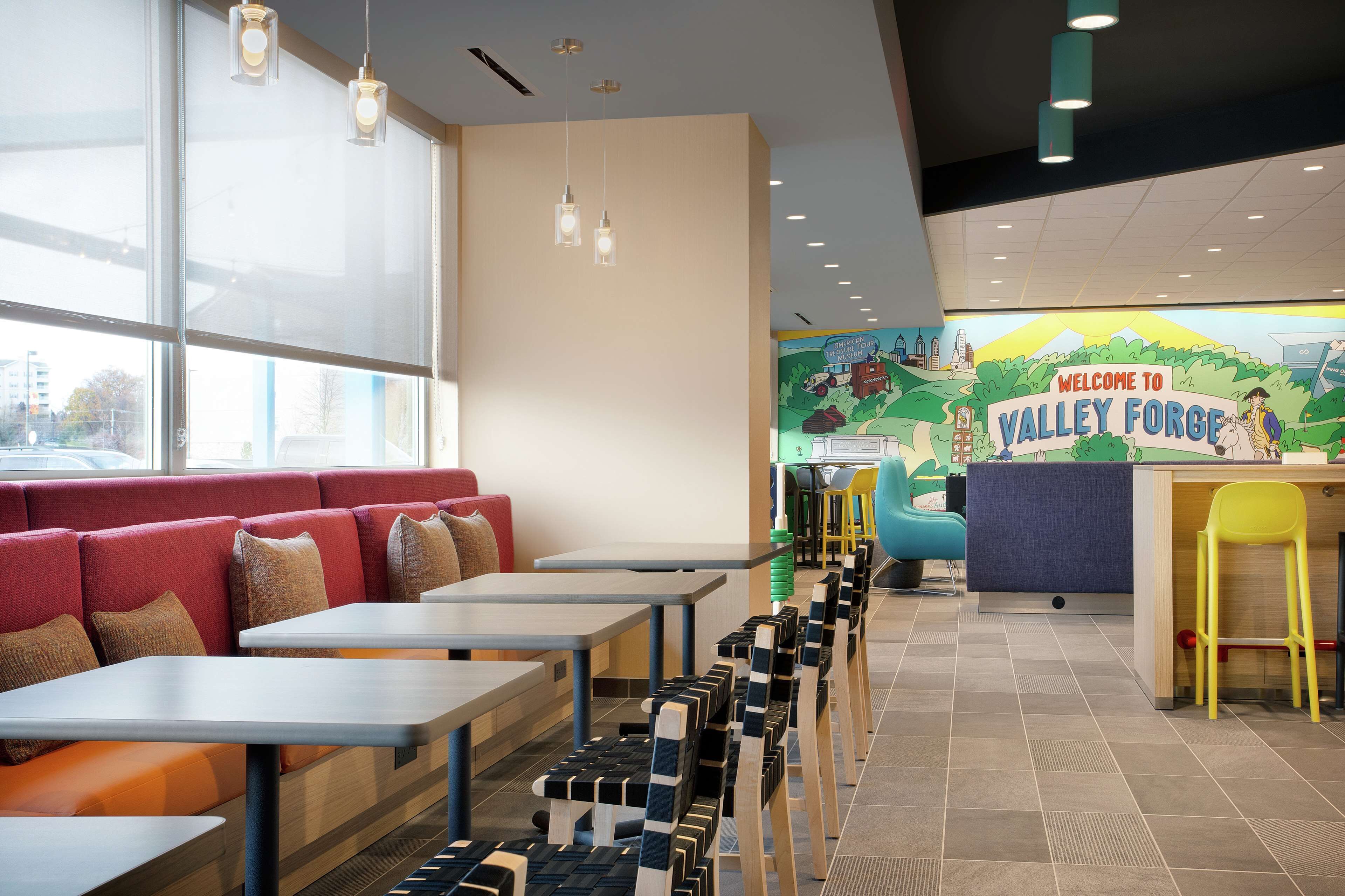 A restaurant with booths, tables, and a mural wall.