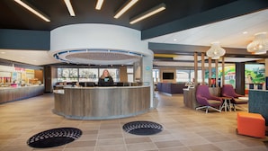 A hotel reception area with a central counter, seating area, and a children's play zone. - Tru by Hilton Audubon Valley Forge (Audubon)