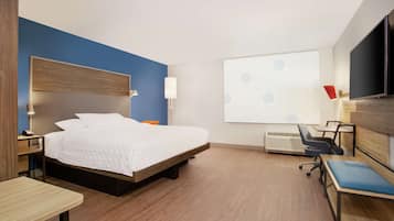 Una habitación de hotel moderna con cama, escritorio, silla y televisor.
