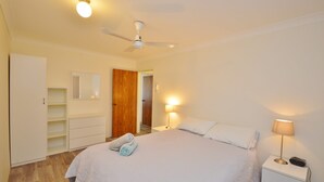 A bedroom with a bed, a nightstand, a lamp, a ceiling fan, and a wardrobe. - Kalbarri Waters A - Kalbarri, WA (Kalbarri)
