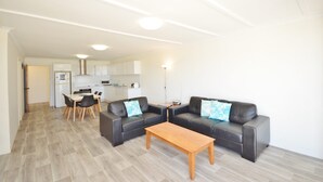 A modern living room with a sofa set, a wooden coffee table, and a dining area with a table and chairs. - Kalbarri Waters A - Kalbarri, WA (Kalbarri)