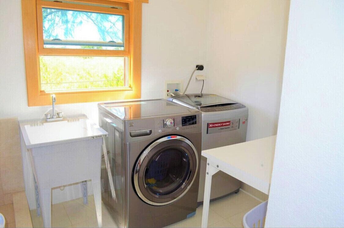 Une petite buanderie équipée d’un lave-linge, d’un sèche-linge et d’un évier.
