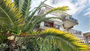 A multi-story building with balconies and a garden with palm trees. - StayInn Villa Bellevue (Nestos)