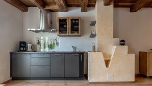 A modern kitchen with dark cabinets, a stainless steel range hood, and a unique wooden structure.